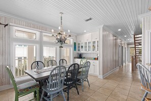A spacious kitchen with white cabinetry, a dining table with chairs, and a chandelier.