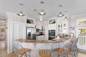 A kitchen with a central island, bar stools, and pendant lighting. - 5BR Gulf-Front Home with Private Beach & Heated Pool ~ Sleeps 12 (Seacrest)