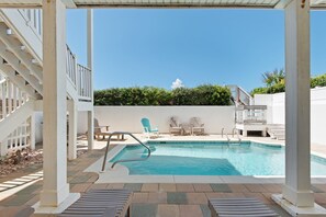 Un espace piscine doté d’une piscine à l’eau cristalline, de chaises longues et d’une structure en forme de pergola.