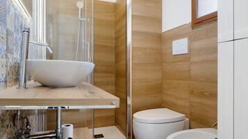 Une salle de bain moderne avec un grand lavabo blanc, des toilettes et un espace douche.