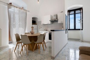 Une cuisine moderne avec des meubles blancs, une table à manger en bois avec des chaises et une grande fenêtre donnant sur un beau paysage.