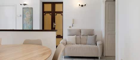 A dining area with a round table and chairs, a sofa, and a door with a traditional design.