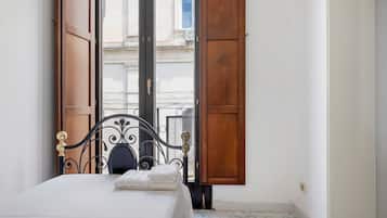 Ein Hotelzimmer mit einem Bett, einem Fenster mit Holzjalousien und Blick auf ein Gebäude.