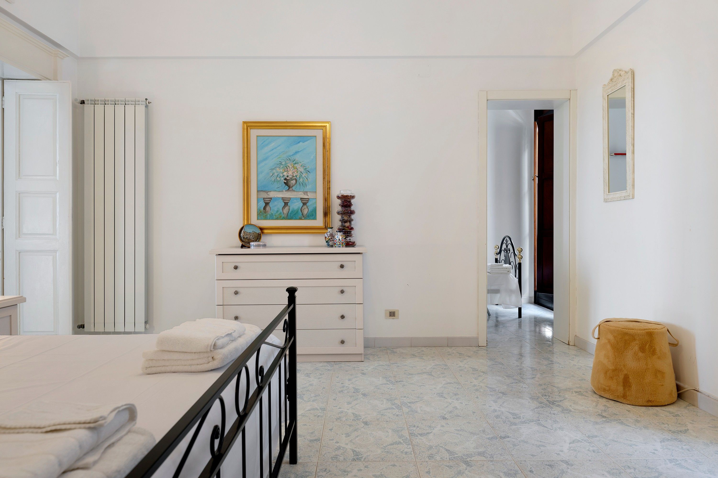 Een slaapkamer met een bed, een dressoir, een schilderij en een spiegel.