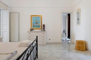 Een slaapkamer met een bed, een dressoir, een schilderij en een spiegel.