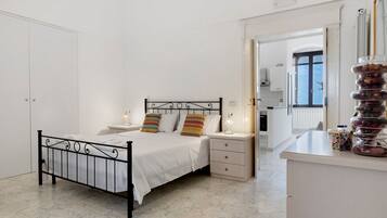 Ein Schlafzimmer mit einem Bett, Nachttischen, einem Spiegel und Blick zur Küche.
