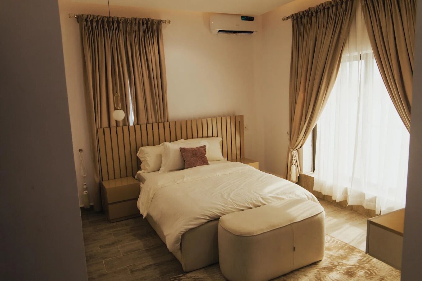 Un dormitorio moderno con una cama grande, un cabecero de madera, una mesita de noche y una ventana con cortinas.
