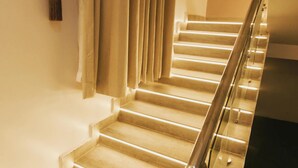 A staircase with a handrail and a light fixture on the wall. - The Embassy Boutique Apartment (Jos)