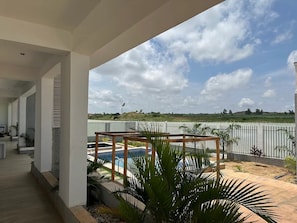 Un espacio al aire libre techado con piscina, palmeras y vistas a un campo.
