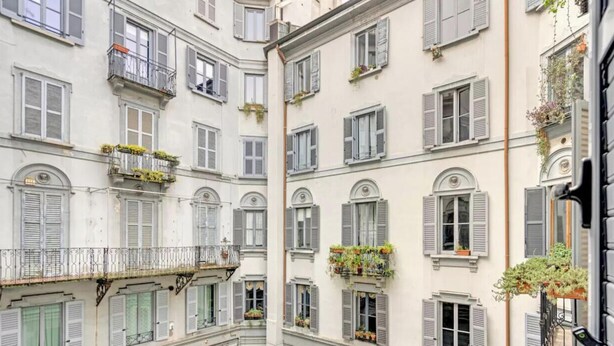 Un immeuble à plusieurs étages doté de balcons, dont certains sont ornés de plantes.