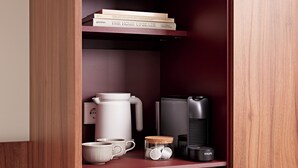 A wooden shelf with a white kettle, a black coffee maker, and a book titled 'THE HOME UPGRADE'.