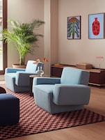 Una sala de estar moderna con un sofá azul, una planta en maceta y obras de arte en la pared.