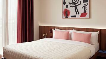 A hotel room with a bed, a nightstand, a framed artwork, and a window with curtains.