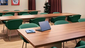 A conference room with multiple tables and chairs, a laptop on one table, and artwork on the walls.