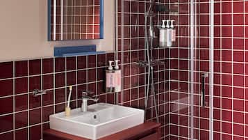 Un baño con lavamanos blanco, un espejo y cabina de ducha.