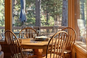 A wooden dining table with chairs, a bowl of popcorn, a glass of water, and a jigsaw puzzle on the table. - Luxury 5BR Forest Retreat at Black Butte Ranch (Sisters)