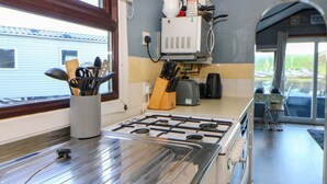 Une cuisine équipée d’une cuisinière à gaz, d’une machine à café et d’ustensiles rangés dans un porte-ustensiles.