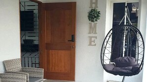 A room with wicker furniture, a hanging chair, and a wooden door. - DraxHall Villa (Saint Ann's Bay)