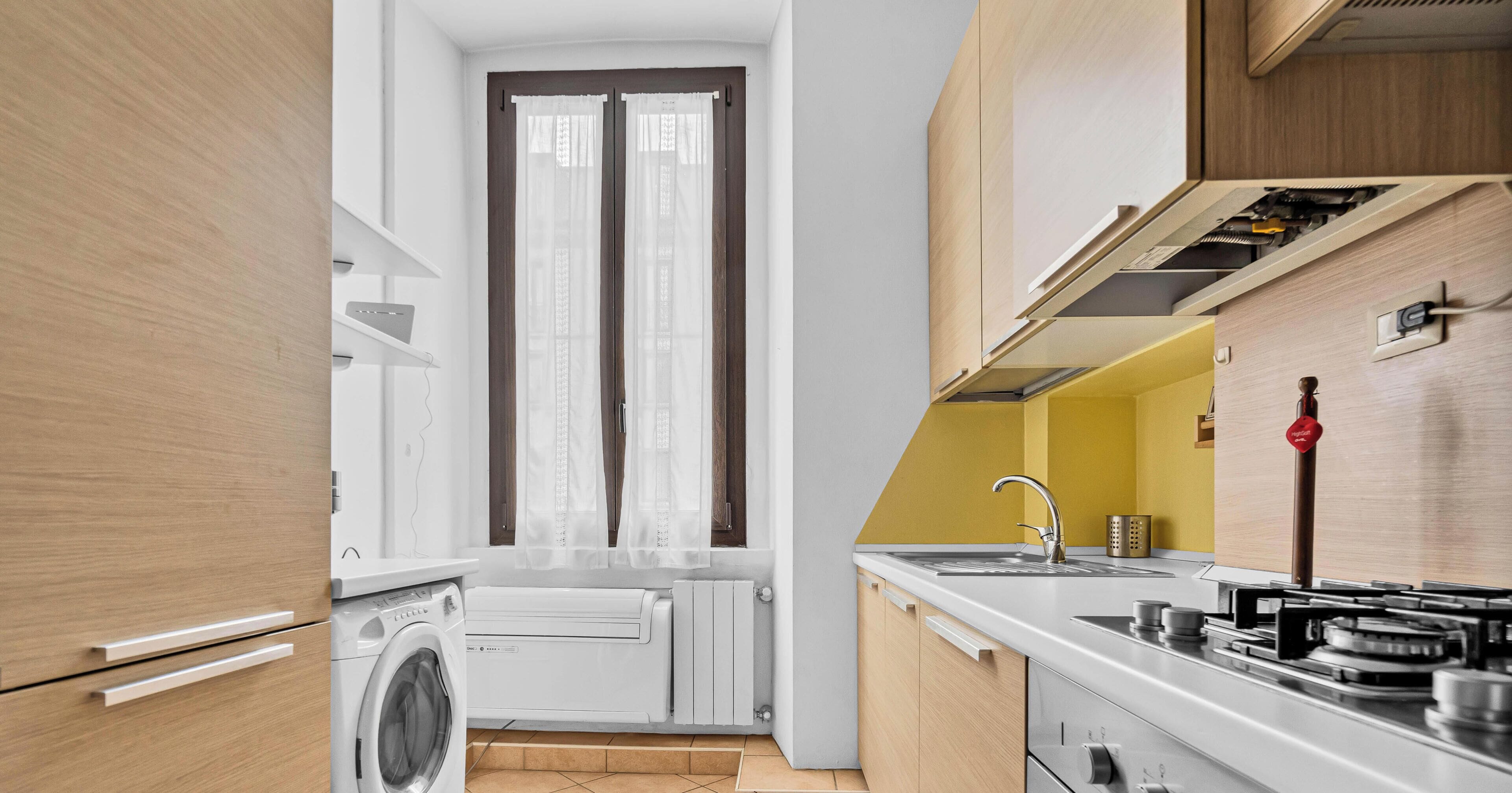 Une cuisine compacte équipée d’un lave-linge intégré, d’une cuisinière et d’un évier.