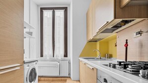 A compact kitchen with a built-in washer, a stove, and a sink. - BLI39 Cozy apartment in the Bocconi area (Milano)