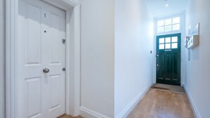 Un couloir avec une porte blanche portant le numéro « 1 » et une porte verte au bout.