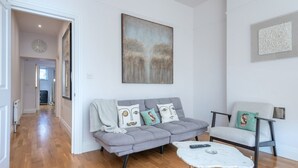 Un salon moderne avec un canapé gris, un fauteuil blanc et une table basse.