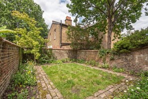 A brick building with a garden in front. - Kilburn Flat w/ Designer Kitchen near Kensal Rise (Greater London)