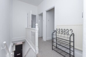 A narrow hallway with white walls, a white door, and a metal rack with hooks. - Kilburn Flat w/ Designer Kitchen near Kensal Rise (Greater London)