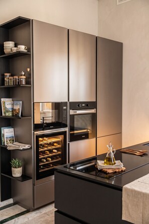 A modern kitchen with built-in appliances, a wine rack, and a small plant. - Sant'Angelo Deluxe Apartment (Roma)