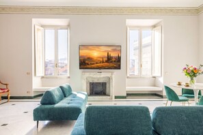 A living room with a fireplace, two windows, a sofa, and a dining area. - Sant'Angelo Deluxe Apartment (Roma)