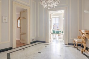 A spacious hallway with marble flooring, ornate gold furniture, and a chandelier. - Sant'Angelo Deluxe Apartment (Roma)