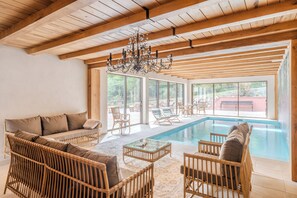 A spacious indoor area with a pool, wicker furniture, and large windows. - Le Buchwald est une chaleureuse maison de famille signée laclefduchateau.com nichée au cœur de la forêt alsacienne. Un lieu authentique où se retrouver, partager de précieux moments et profiter de la nature. (Dambach)