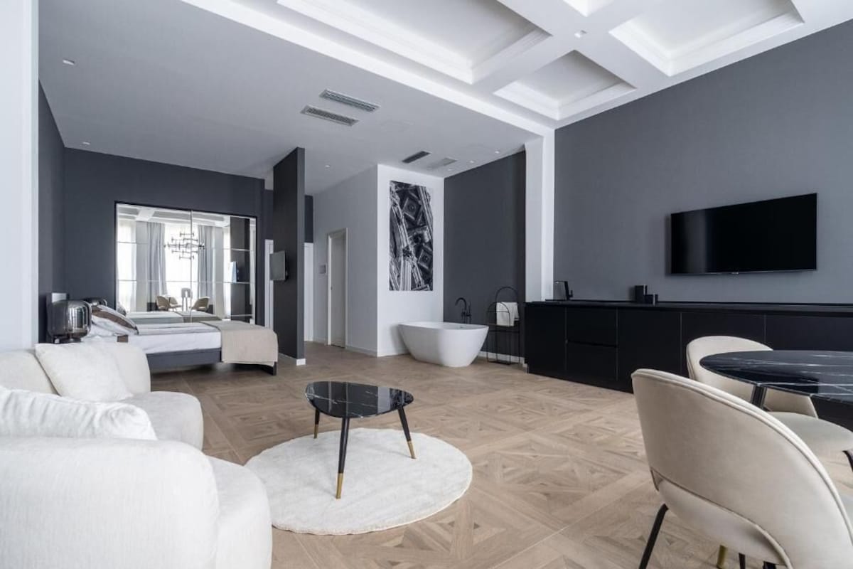A modern living room with a sofa, a round coffee table, a TV, and a large mirror.