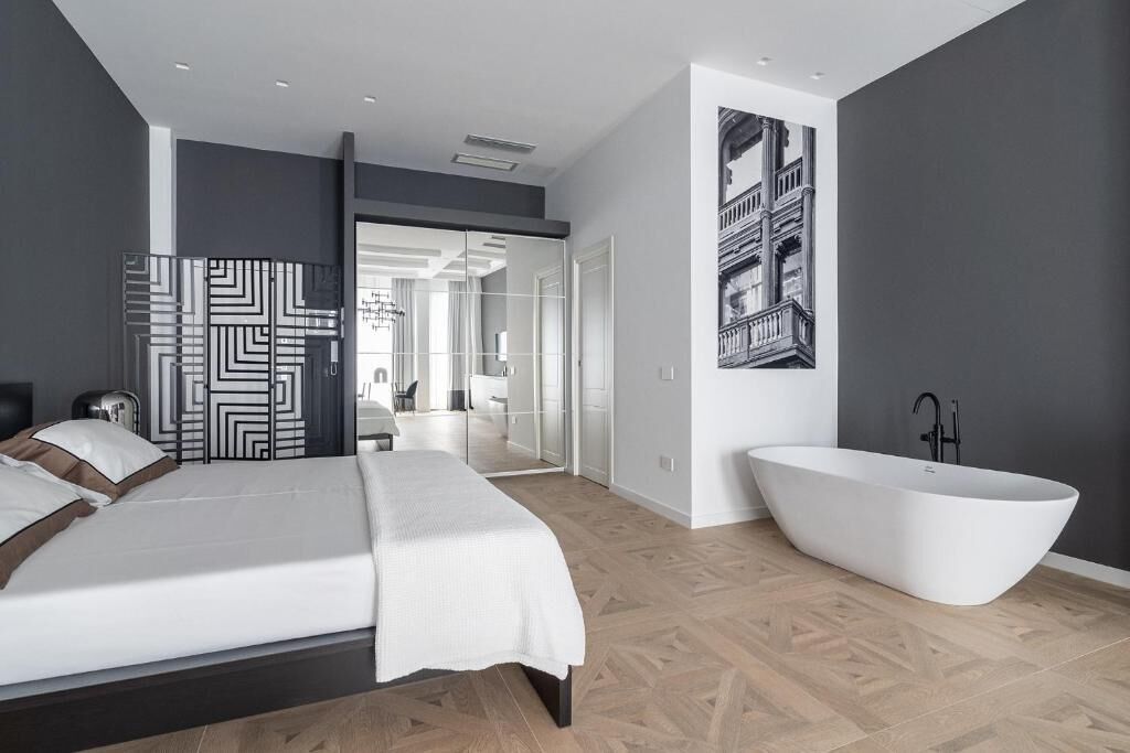 Une chambre moderne avec un grand lit, une baignoire sur pieds et une armoire avec des portes miroir.