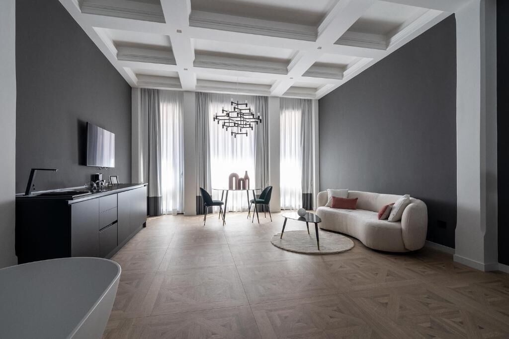 A modern living room with a sofa, a coffee table, and a dining area with chairs.