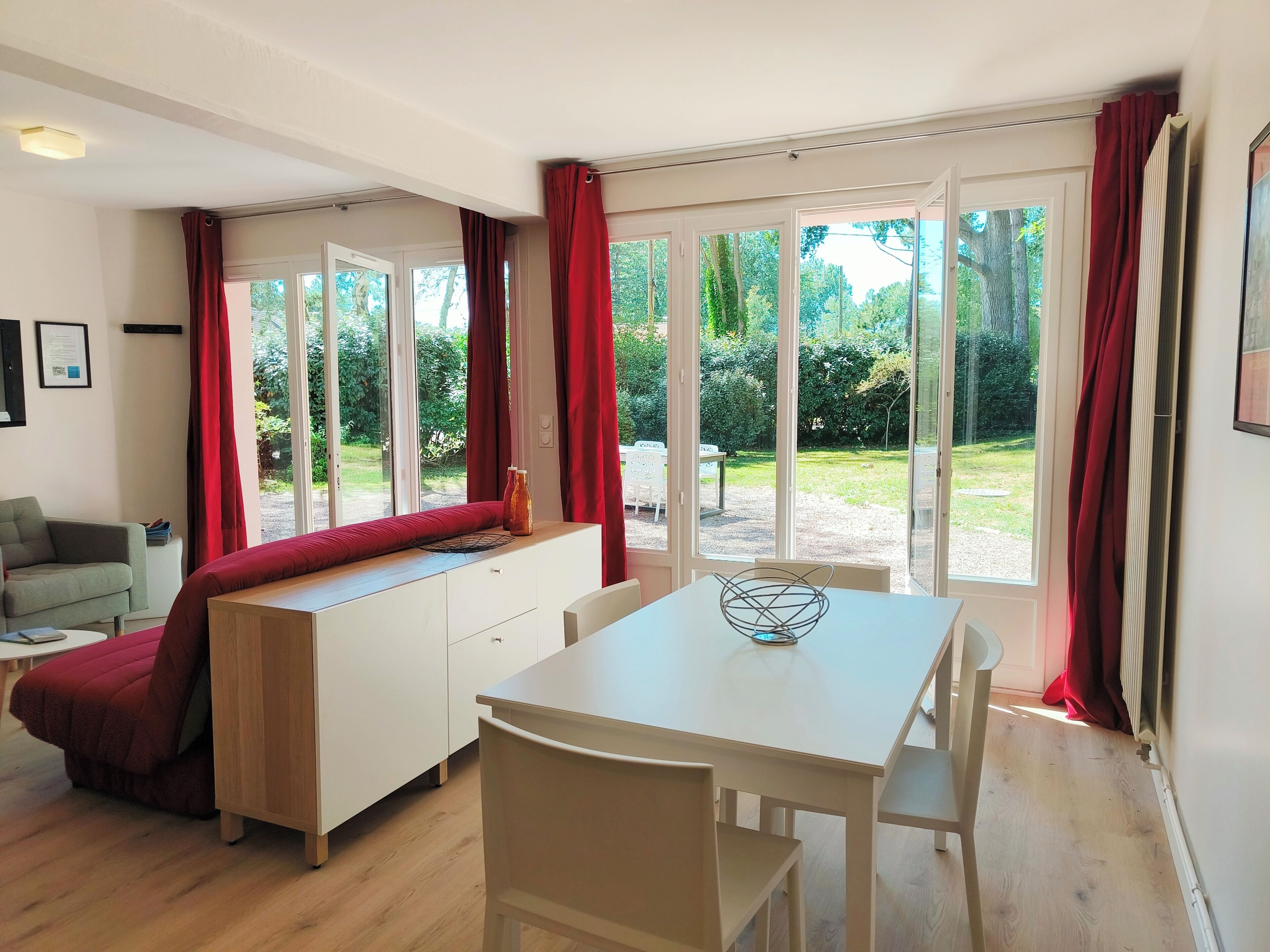 Une cuisine moderne avec une table à manger, un banc et une vue sur le jardin grâce à de grandes fenêtres.