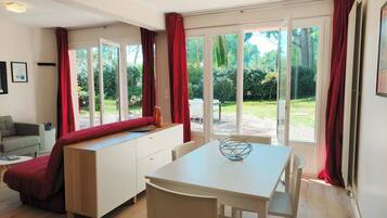 Une cuisine moderne avec une table à manger, un banc et une vue sur le jardin grâce à de grandes fenêtres.