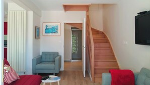 Un salon avec un canapé, un fauteuil, une petite table et un escalier.