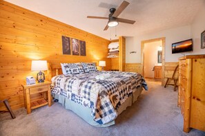 A wooden cabin bedroom with a bed, two bedside tables, a ceiling fan, a television, and a wooden dresser. - Bear Ridge | Luxury 3BR Smoky Mountain Cabin | Hot Tub, Game Room & Pool Access (Gatlinburg)