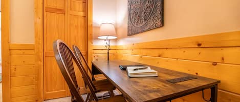Una habitación con paneles de madera, una mesa, sillas, una lámpara y un adorno en la pared.