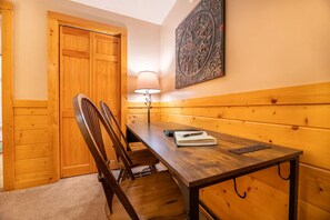 A wooden-paneled room with a table, chairs, a lamp, and a decorative wall piece. - Bear Ridge | Luxury 3BR Smoky Mountain Cabin | Hot Tub, Game Room & Pool Access (Gatlinburg)