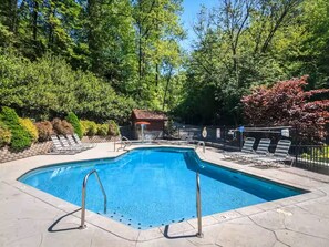 A rectangular swimming pool with two ladders, surrounded by a paved deck and a fence. - Bear Ridge | Luxury 3BR Smoky Mountain Cabin | Hot Tub, Game Room & Pool Access (Gatlinburg)