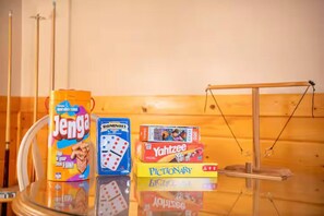 A table with a glass top displaying various board games including Jenga, Dominoes, and Yahtzee. - Bear Ridge | Luxury 3BR Smoky Mountain Cabin | Hot Tub, Game Room & Pool Access (Gatlinburg)