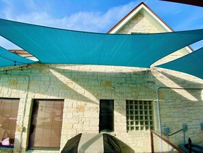 Ein Steinhaus mit einem Giebeldach, einer überdachten Außenfläche und einem Fenster mit Metallgitter.