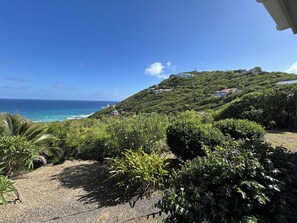 Un paysage côtier avec vue sur la mer, une colline verdoyante et un bâtiment situé au sommet.