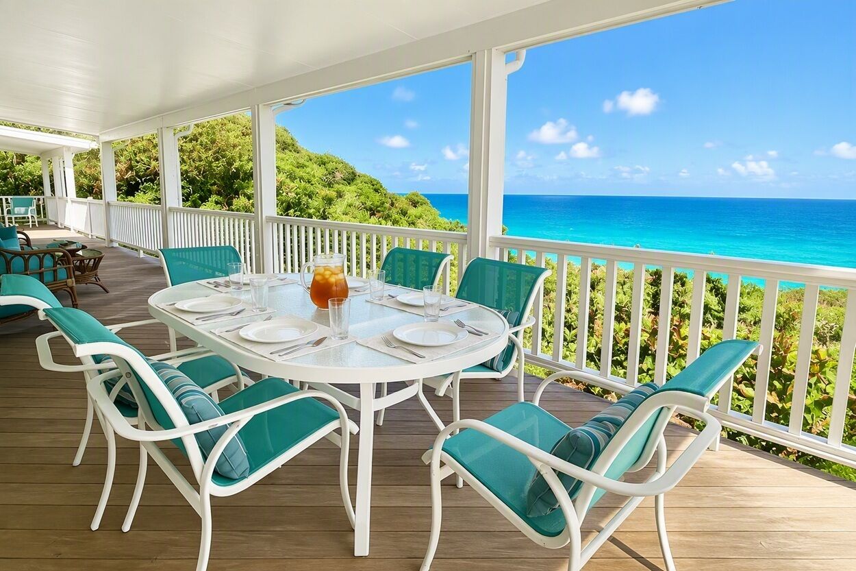 A covered outdoor dining area with a view of the ocean.