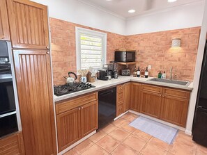 A kitchen with wooden cabinets, a microwave, a stove, and a sink. - Brizan Villa – Private 3 Bedroom Caribbean Retreat with Pool, Hot Tub & Stunning Reef Bay Views in St. John, USVI (St John)