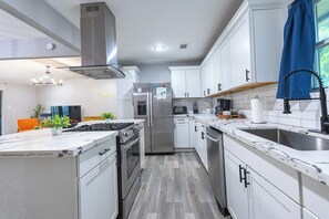 Eine moderne Küche mit weißen Schränken, Edelstahlgeräten, einer Marmorarbeitsplatte und einem eingebauten Backofen.