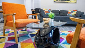 A modern living room with a vibrant geometric rug, a sofa, a chair, and a coffee table with a plant. - Outdoor Cinema | Hot Tub | Fire Pit | Huge Yard (Houston)