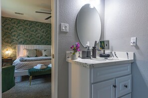 Een hotelkamer met een bed, een kaptafel met spiegel en een kleine plant in pot.